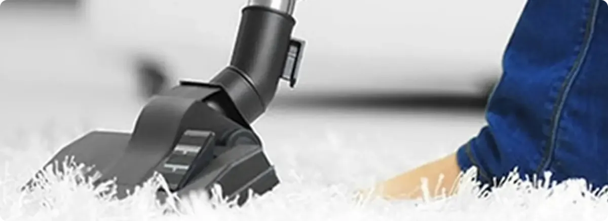 Close-up of a professional vacuuming a white carpet in Midway.